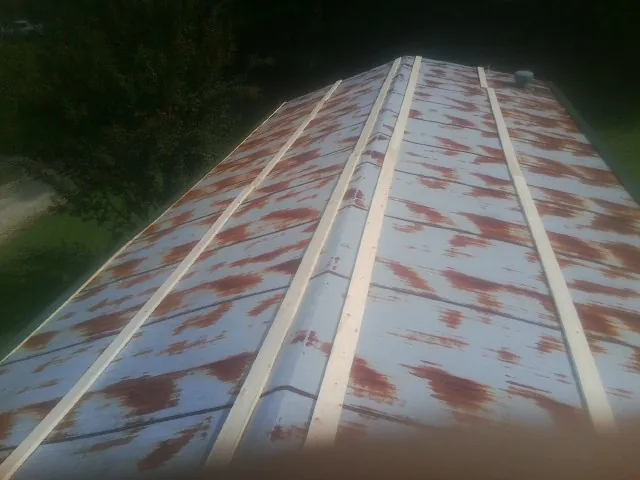 Rusted metal roof panels with new wood purlins before replacement — Storm Damage Roof Repair in Blackstone by Roofing Brothers