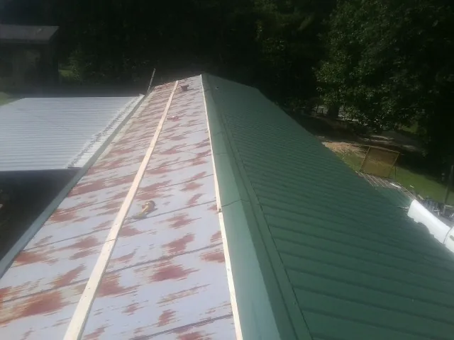 Old rusted panels beside newly installed green metal roofing — Wind Damage Roof Repair by Roofing Brothers in Blackstone