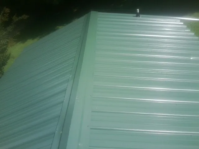 New green metal panels meeting at the ridge of a roof — Flat Roof Repair work by our crew in Blackstone
