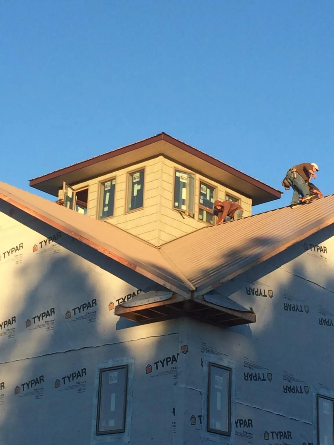 Roofers working around a rooftop cupola on a new metal roof at sunset — Roof Waterproofing in Blackstone by Roofing Brothers